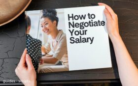 A hardback book against the backdrop of a textured black desk. The book is titled How to Negotiate Your Salary.